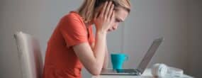 A woman looking dejected at her laptop after being scammed