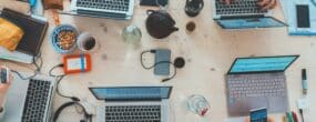 A desk of people working with computers and other technology